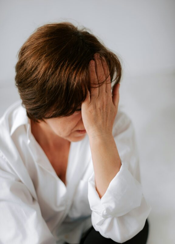 Stressed Woman Holding Her Head – Skin Concerns and Mental Fatigue
